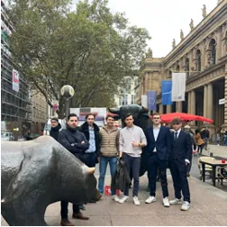 Gruppe von Studierenden neben der Bullen-Skulptur vor dem Gebäude der Frankfurter Wertpapierbörse.